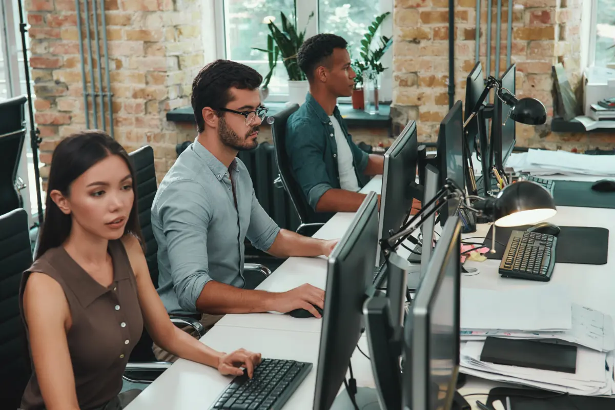 Group of young employees working on computers while sitting in modern open space